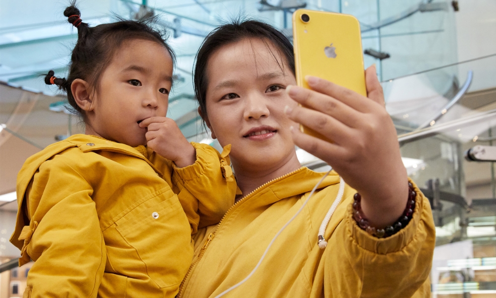 Woman holding child taking selfie with iPhone XR