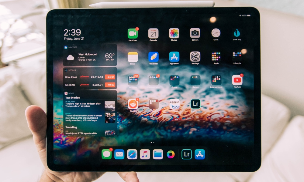 hand holding iPad with home screen and widgets