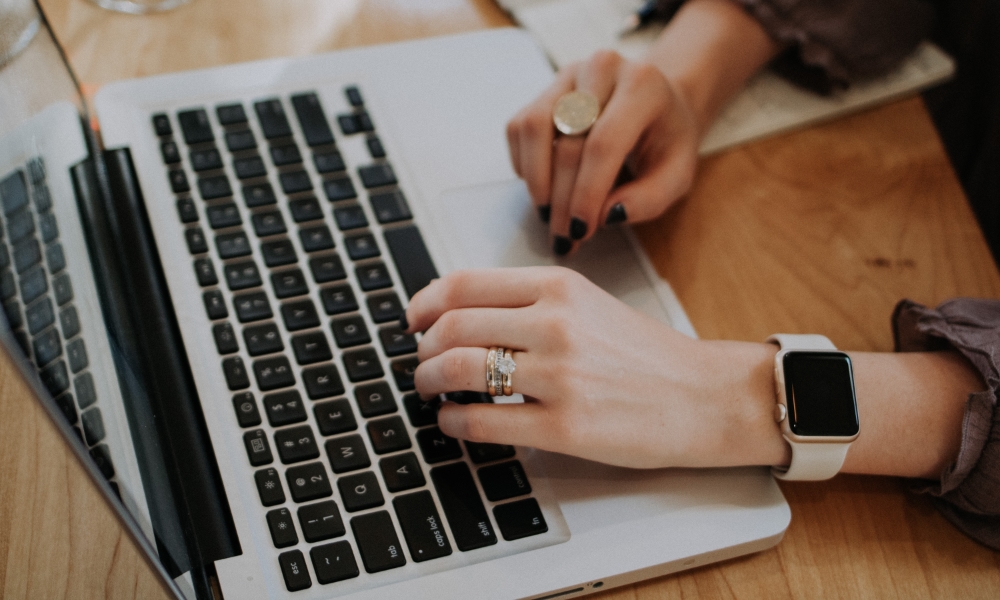 person using MacBook wearing Apple watch