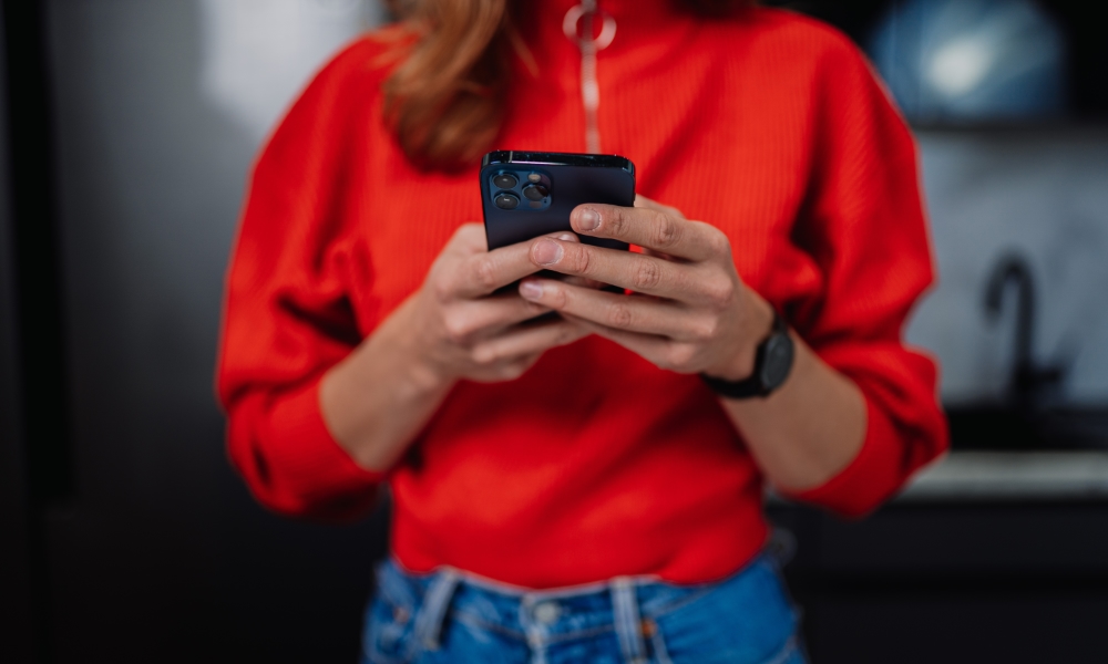 woman standing and typing on iphone