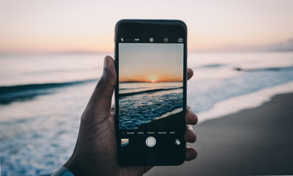 person taking a picture of a sunset on an iPhone