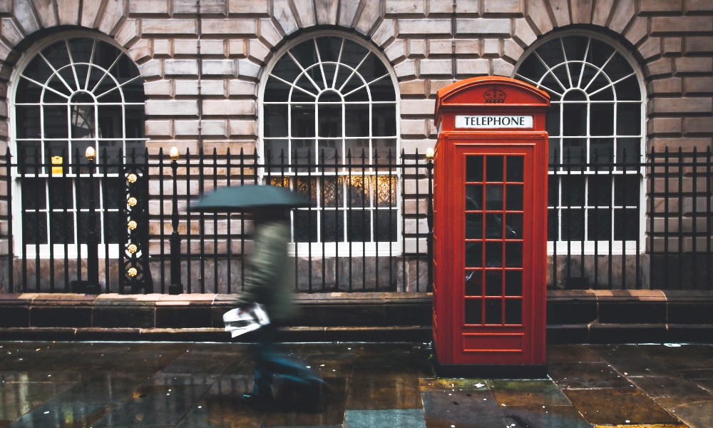 person walking by telephone box on London UK street