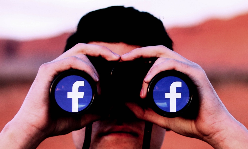 man looking through binoculars with Facebook logo on lenses