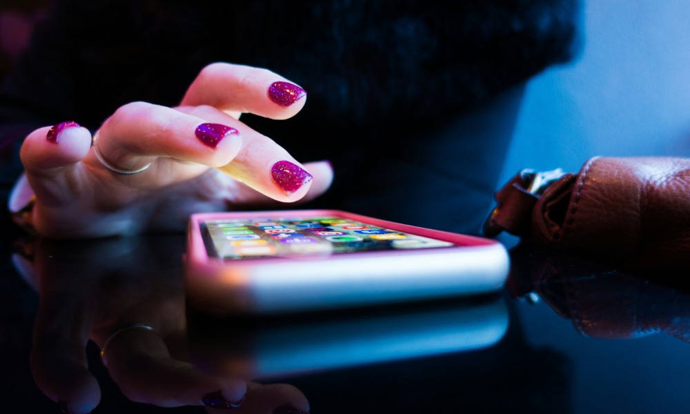 womans hand tapping on iPhone laying on table