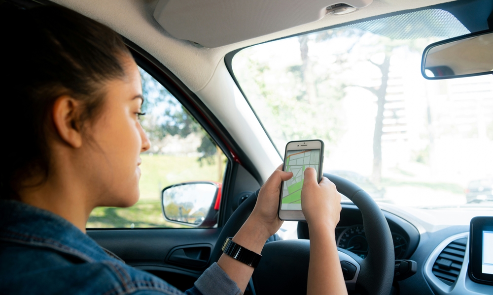 person holding iPhone with maps app in car