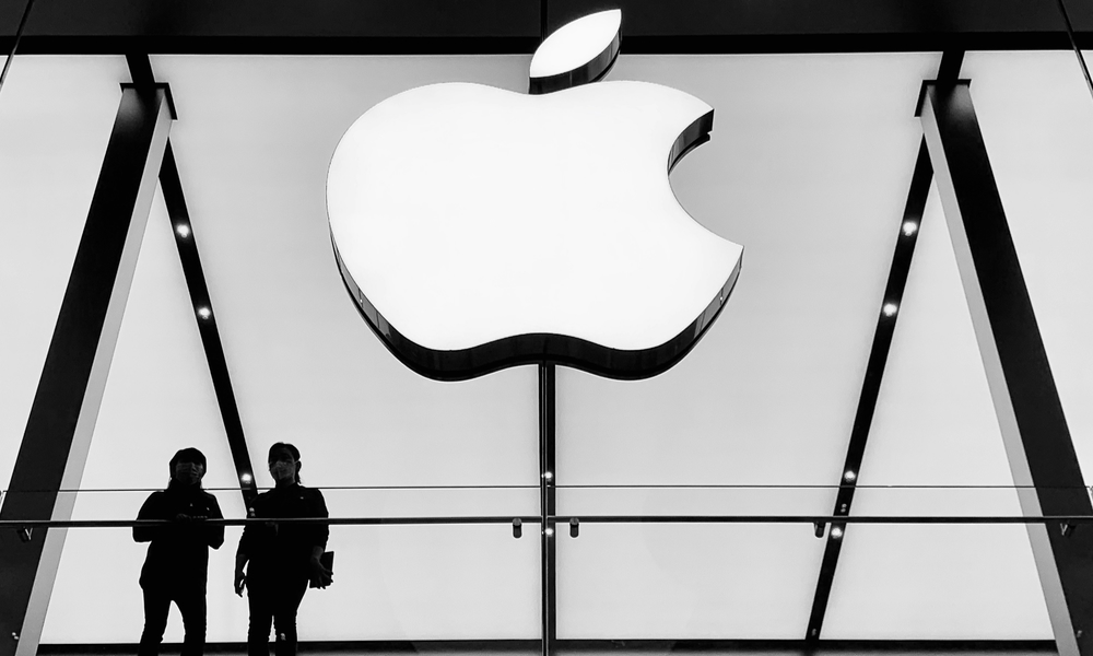 two people silhoutted in front of large Apple logo