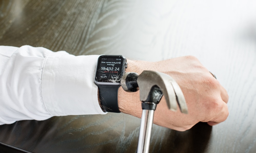 Businessman breaking Apple Watch with hammer