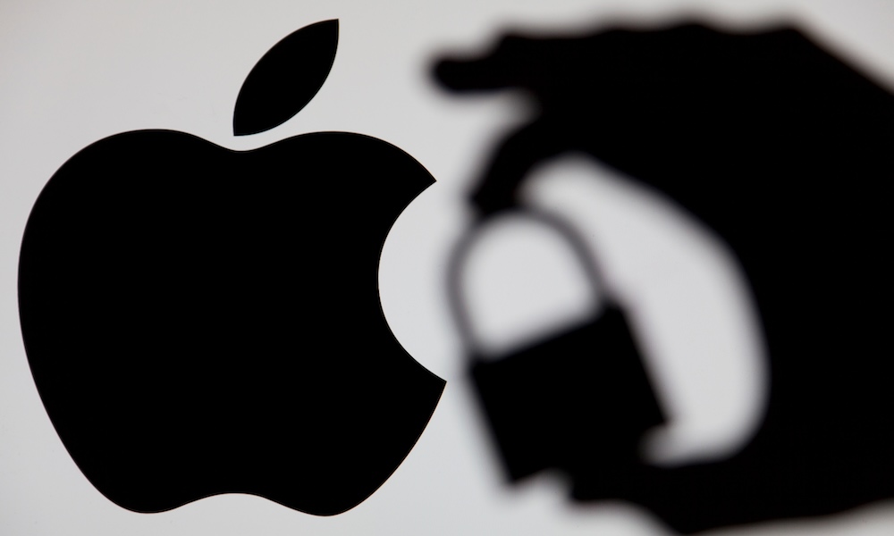 LONDON, UK MAY 15th 2017: Apple security issues. Silhouette of a hand holding a padlock infront of the apple logo LONDON, UK MAY 15th 2017: Apple security issues. Silhouette of a hand holding a padlock infront of the apple logo