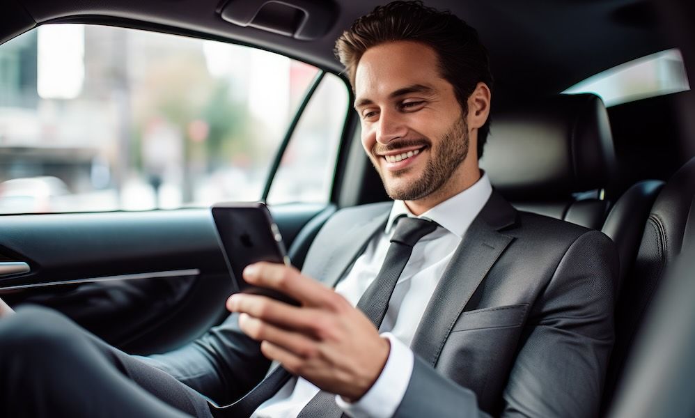 Businessman inside of a car looking at the mobile phone or using mobile phone