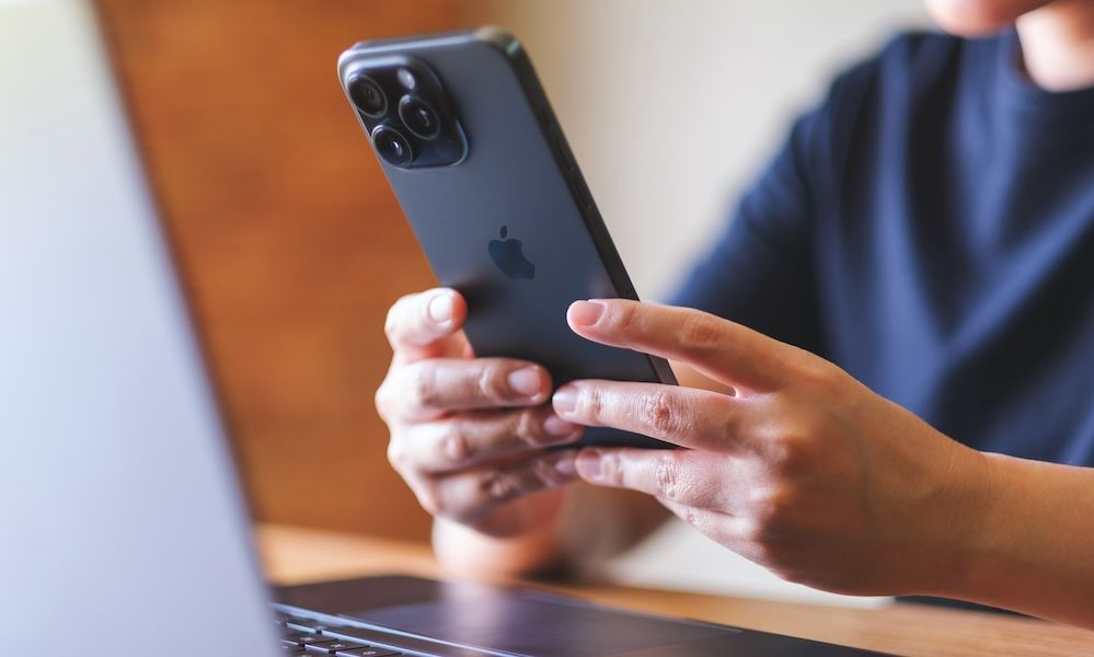 Feb 27th 2024 : A woman using Iphone 15 Pro max smartphone and laptop computer at home, Chiang mai Thailand