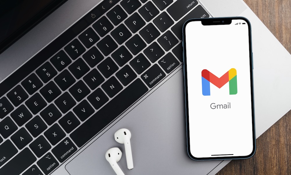 Gmail app on the smartphone screen on wooden background with a computer beside it. Top view. Rio de Janeiro, RJ, Brazil. August 2021.