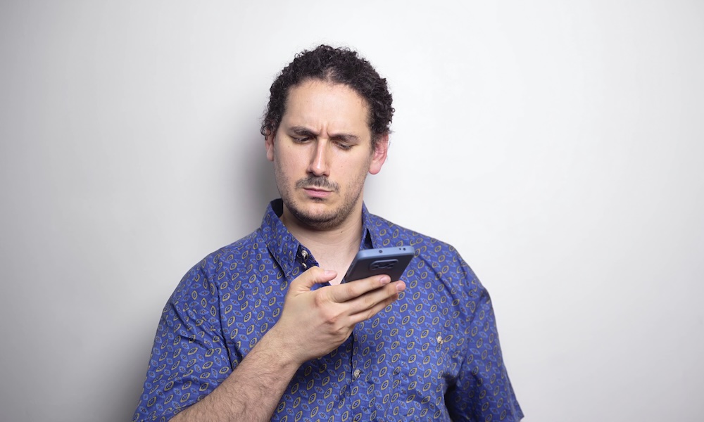 phone fraud concept. Young male distrusts text message