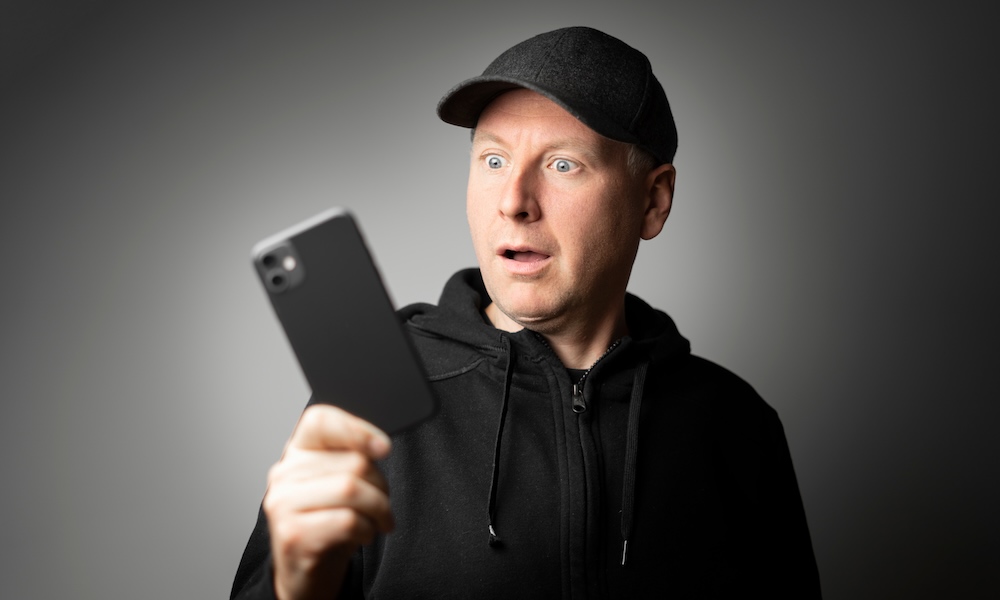 Man in black shocked with the message on the phone or phone itself