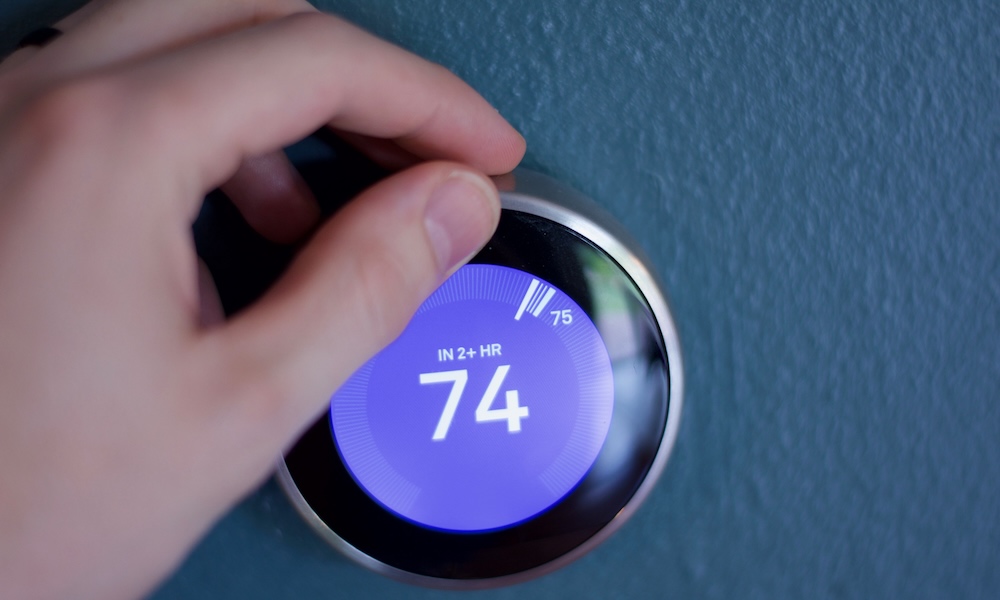 Smart learning thermostat on blue wall.
