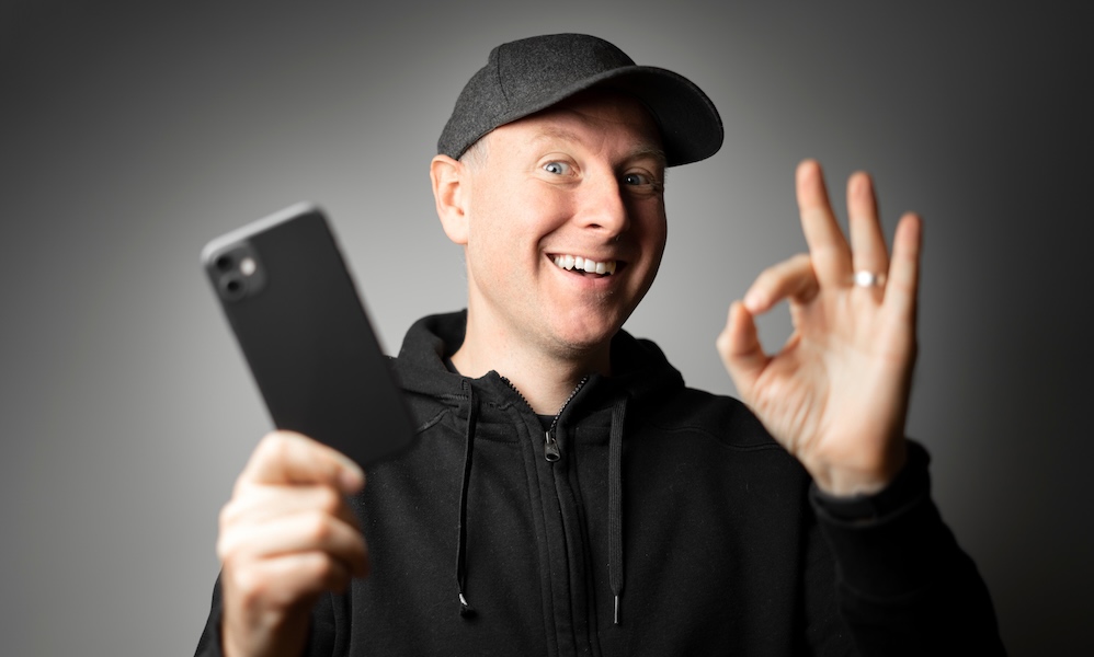 Man in black happy with the message on the phone or the phone itself