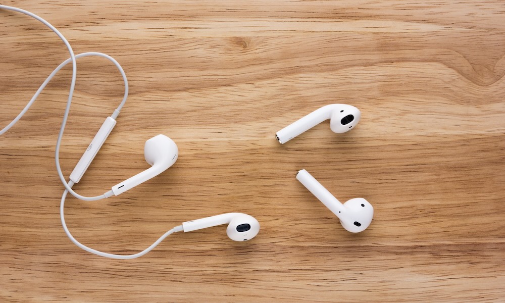 Rostov on Don, Russia September 2018:Airpods and Earpods are lying on a wooden surface. Two pairs of headphones from apple on a wooden table.