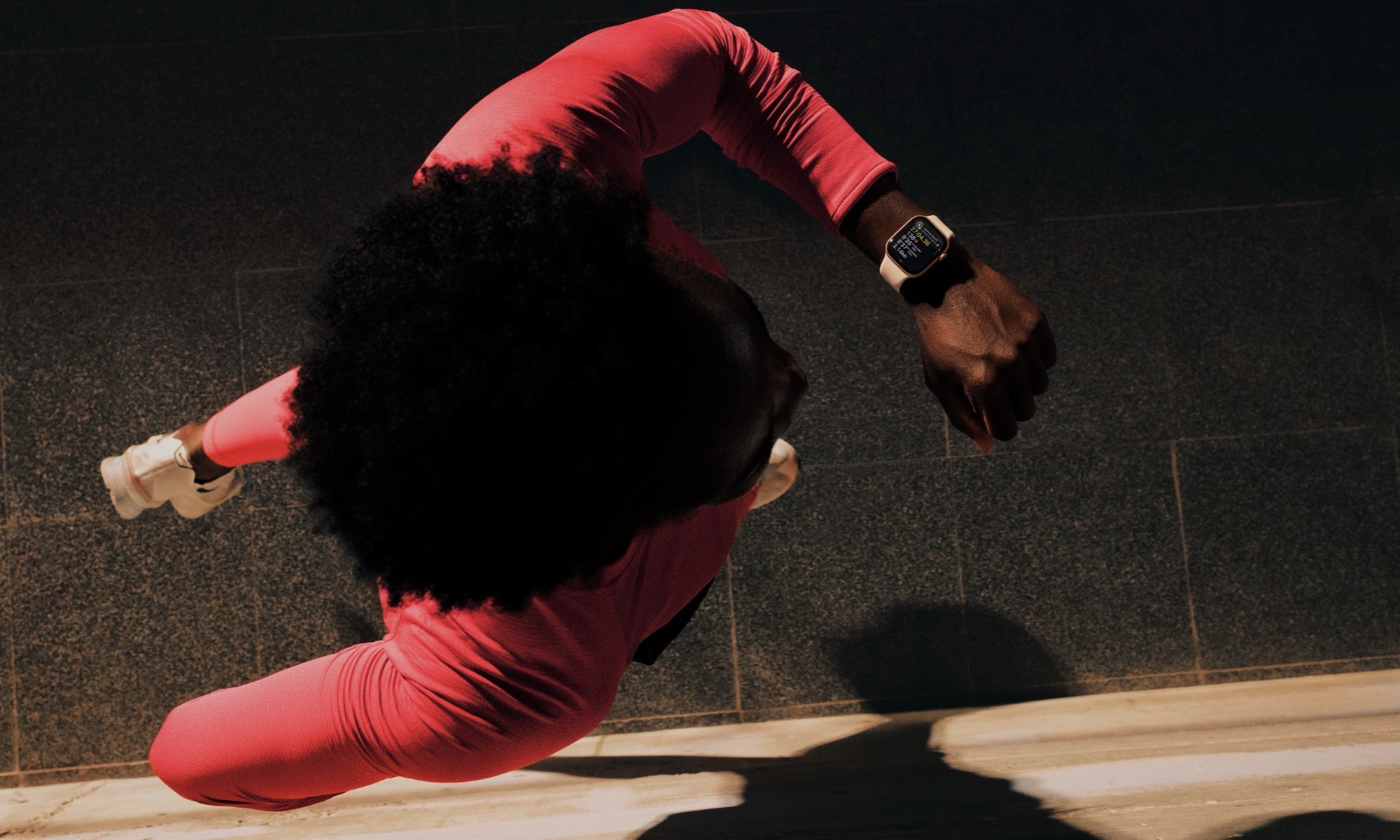 an overhead view of a person running while looking at an Apple Watch Series 11 on their wrist.
