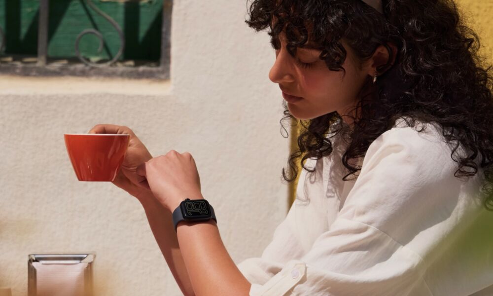 woman in cafe looking at her Apple Watch