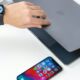 person opening MacBook wearing Apple Watch with iPhone