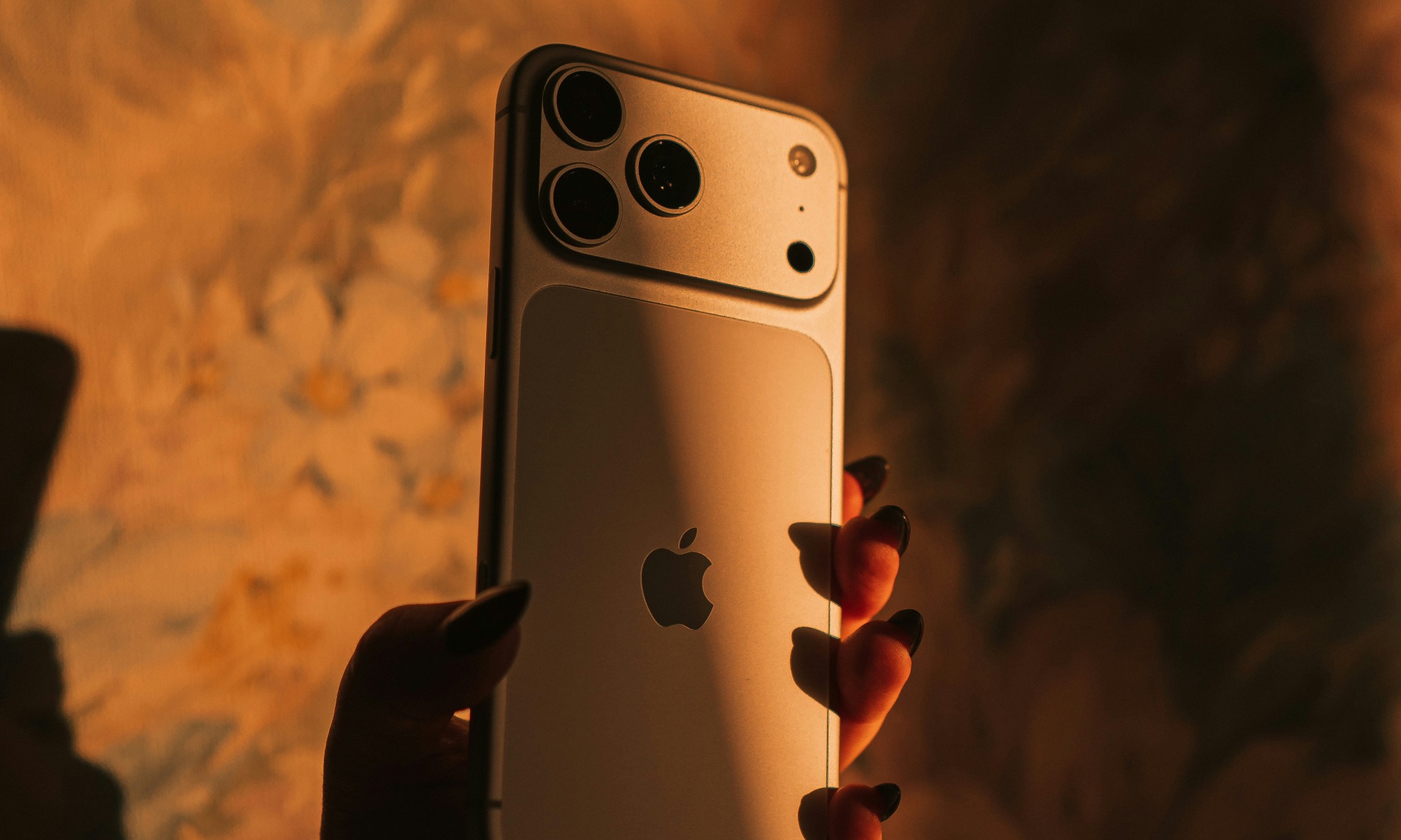 iPhone 17 Pro cosmic orange in hand against orange background