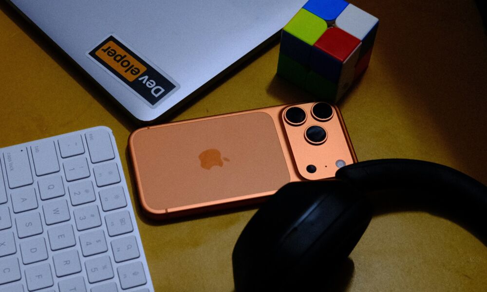 iPhone 17 Pro cosmic orange on desk with laptop keyboard headphones