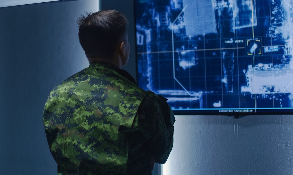 Military Man / Army Officer Watches Satellite Surveillance Footage / Car Tracking of the Target on Wall TV Screen. Secret Military Spying Operation in the Surveillance Center / System Control Room.