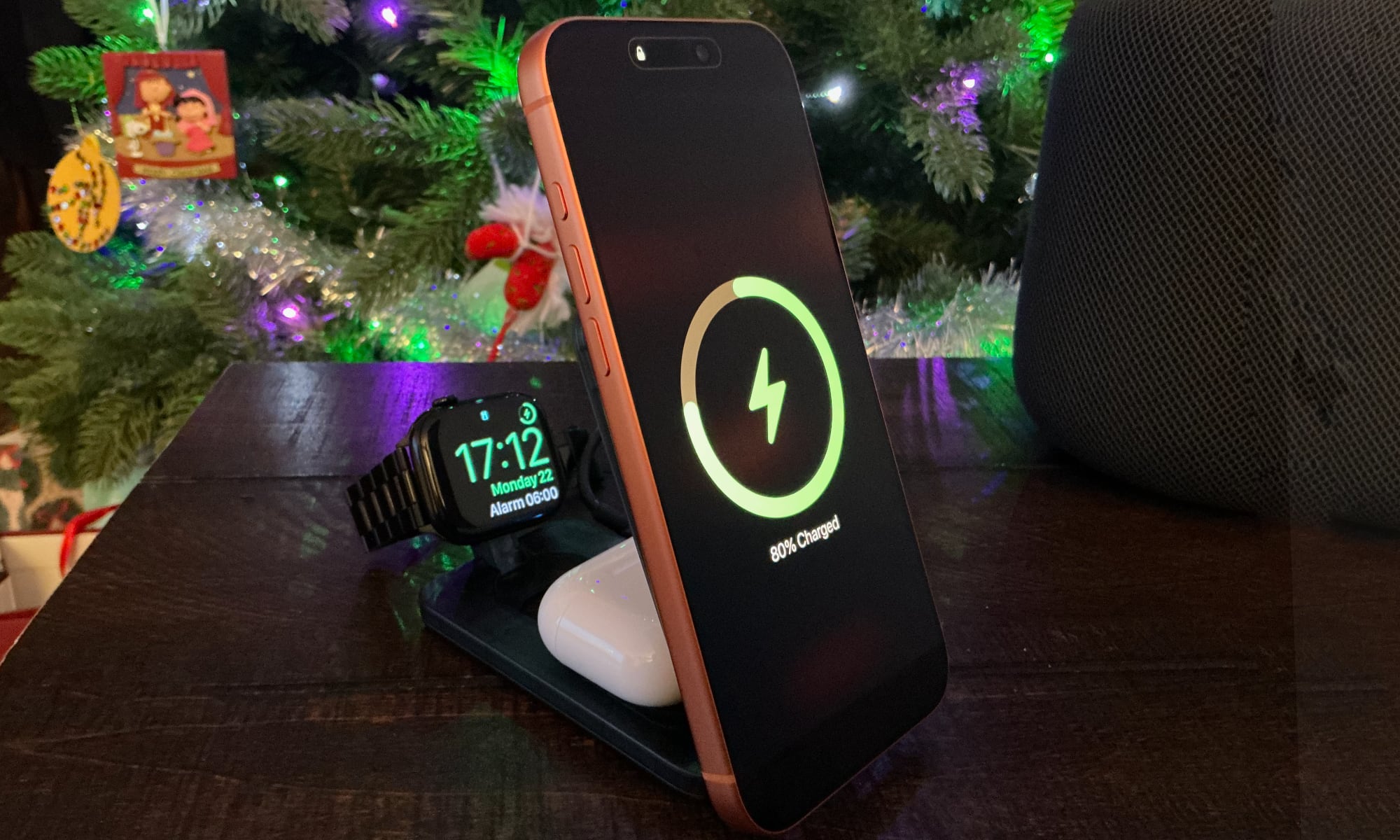 iPhone 17 Pro Max, AirPods, and Apple Watch on ESR 3 in 1 folding charger on a table in front of a Christmas tree.