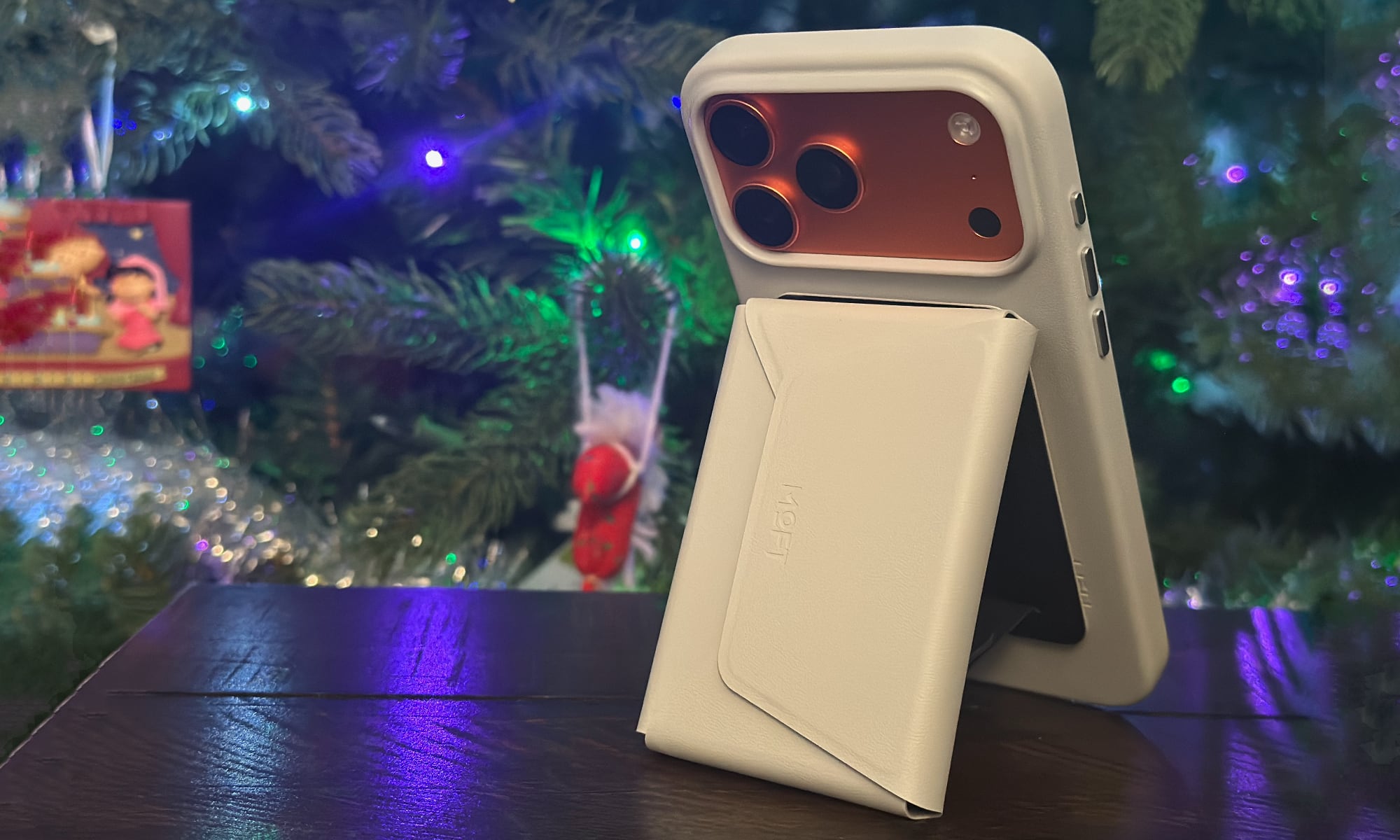 MOFT Movas Snap Case propped up with Snap Field Wallet stand with a Christmas tree in the background.