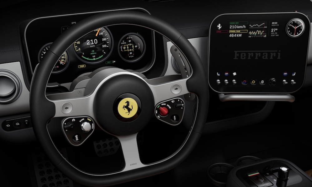 Close-up of the Ferrari Luce steering wheel and driver cockpit featuring tactile physical controls and a central analog G-force meter designed by Jony Ive.