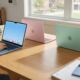 A collection of colorful, slim aluminum MacBooks in pink, blue, and green on a sunlit student desk.