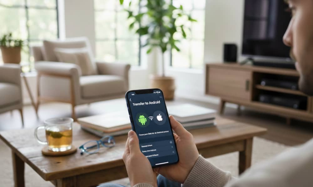 A person using an iPhone to initiate a "Transfer to Android" process in iOS 26.3 while sitting in a modern, sunlit living room.