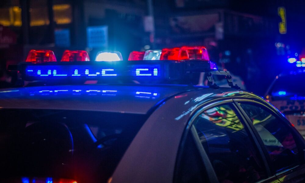 Close-up of blue and red flashing emergency lights on top of a police car at night.