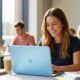 A student using a colorful new budget MacBook in a sunlit university common area.