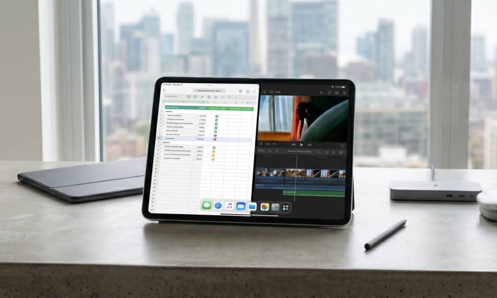 A concept rendering of an unfolded, large-screen "iPad Fold" resting on a concrete desk in a light-filled creative studio. The seamless flexible display is active, showing a multitasking interface with a spreadsheet on the left and a video editing timeline on the right, spanning the center crease.