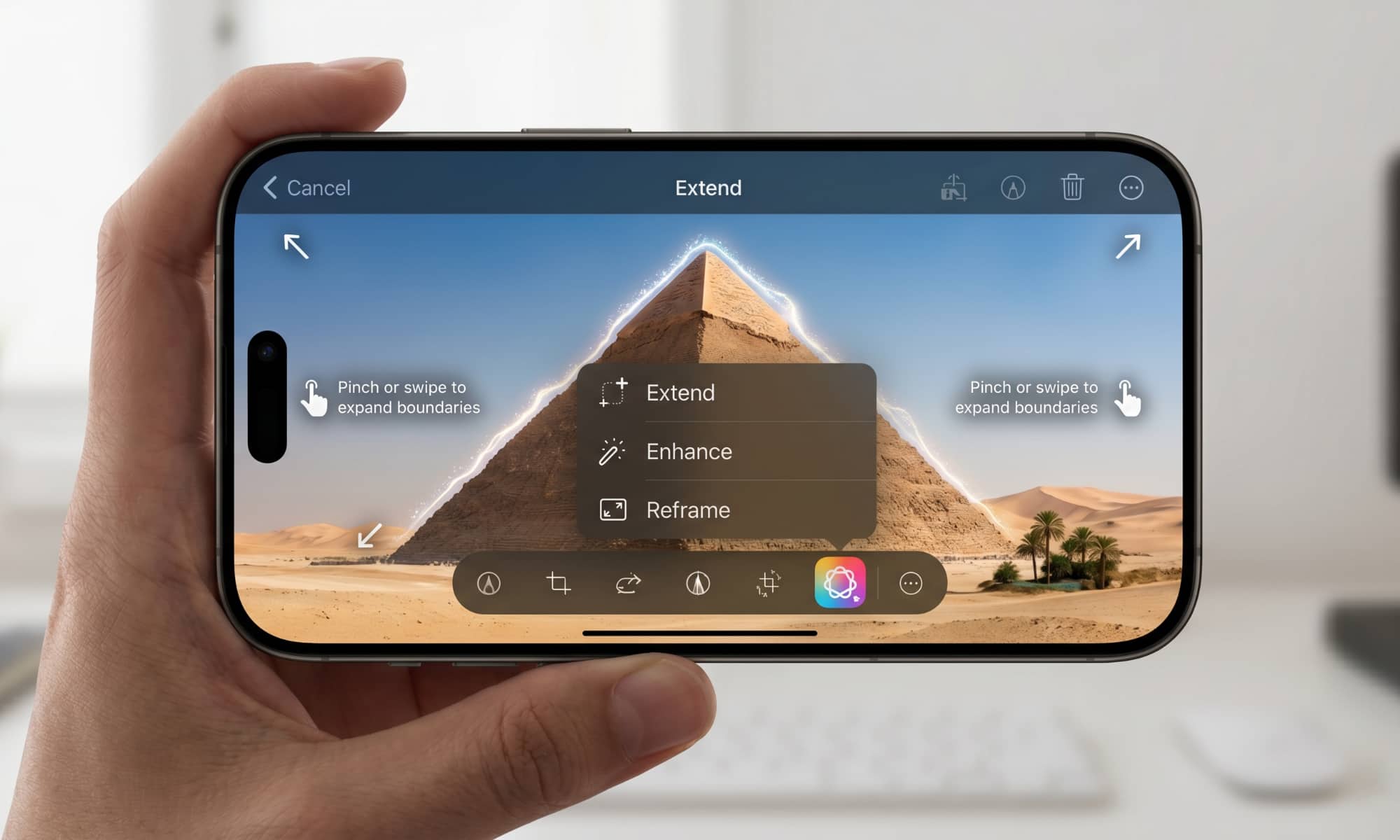 A photograph of a person holding an iPhone in landscape mode. The screen displays an advanced photo editing interface featuring a photo of a pyramid in a desert landscape. A floating menu shows options for "Extend," "Enhance," and "Reframe." Corner arrows and gesture icons indicate how to expand the image's boundaries, accompanied by the on-screen instruction text, "Pinch or swipe to expand boundaries."