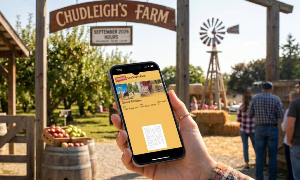 A high-resolution photo of a hand in a flannel cuff holding an iPhone to present an Apple Wallet ticket at a rustic farm entrance gate.