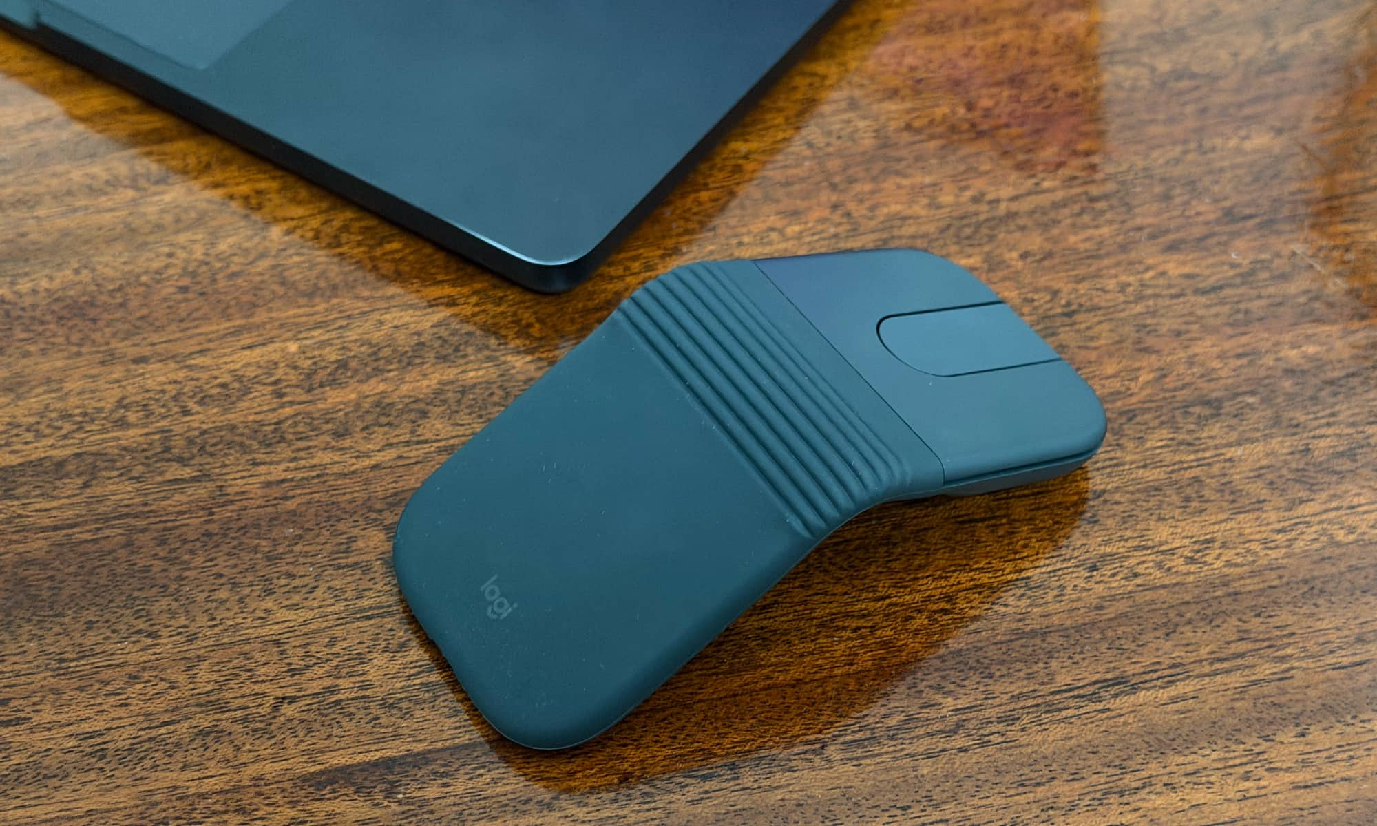A Logitech Mobi Fold on a wooden table beside a MacBook Pro.