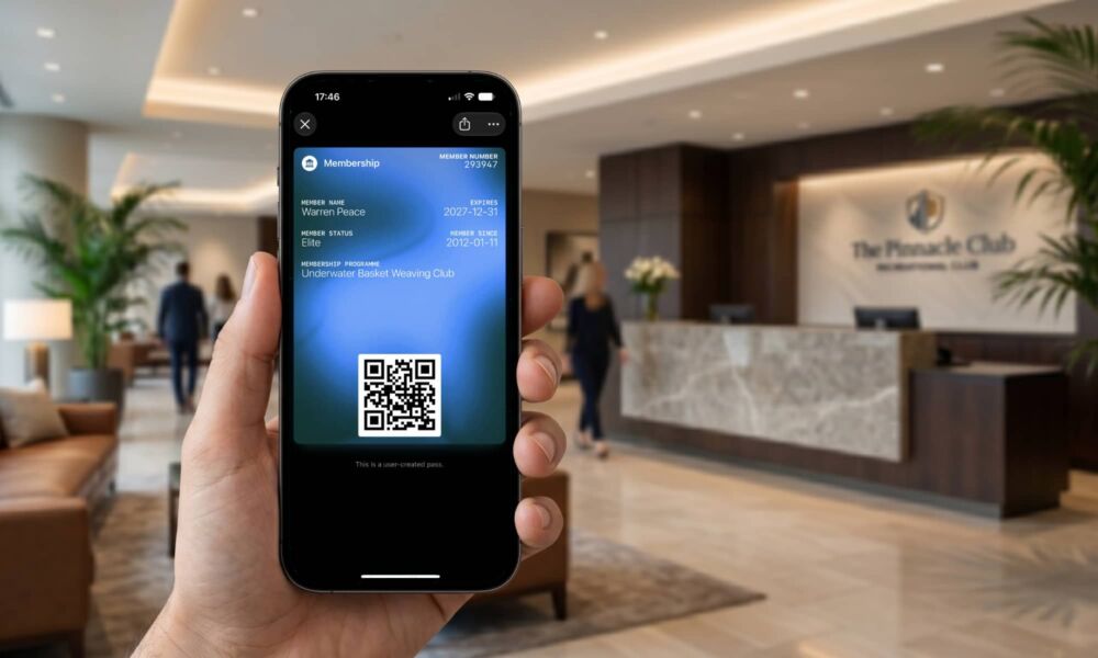 Hand holding an iPhone 17 Pro Max displaying a custom club membership pass with a QR code in the Apple Wallet app on iOS 27 beta.