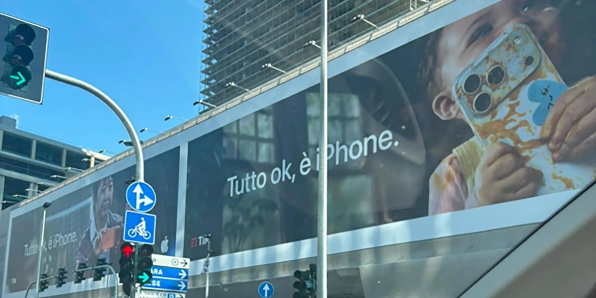 A photograph of Apple's "Relax, it's iPhone" billboard in Milan, Italy, featuring a messy toddler holding an iPhone.