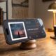 A photo of an iPhone Pro propped on a wooden stand in a cozy home office, displaying the new Apple Music landscape 