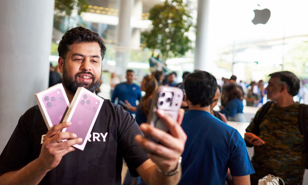 A customer takes a selfie while holding two iPhone 18 Pro boxes at Apple BKC in Mumbai.