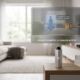 Conceptual rendering of Apple's J450 smart home AI camera, a sleek silver cylinder sitting on a wooden table in a living room. A digital overlay demonstrates how the sensor analyzes room activity — detecting a child playing and a dog resting — without saving or streaming actual video footage.
